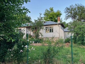 Una casa con jardín cercado, rodeada de vegetación.