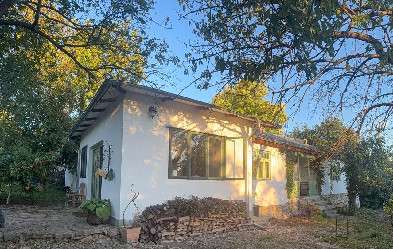 Una casa blanca con techo inclinado, una chimenea y un pequeño porche.