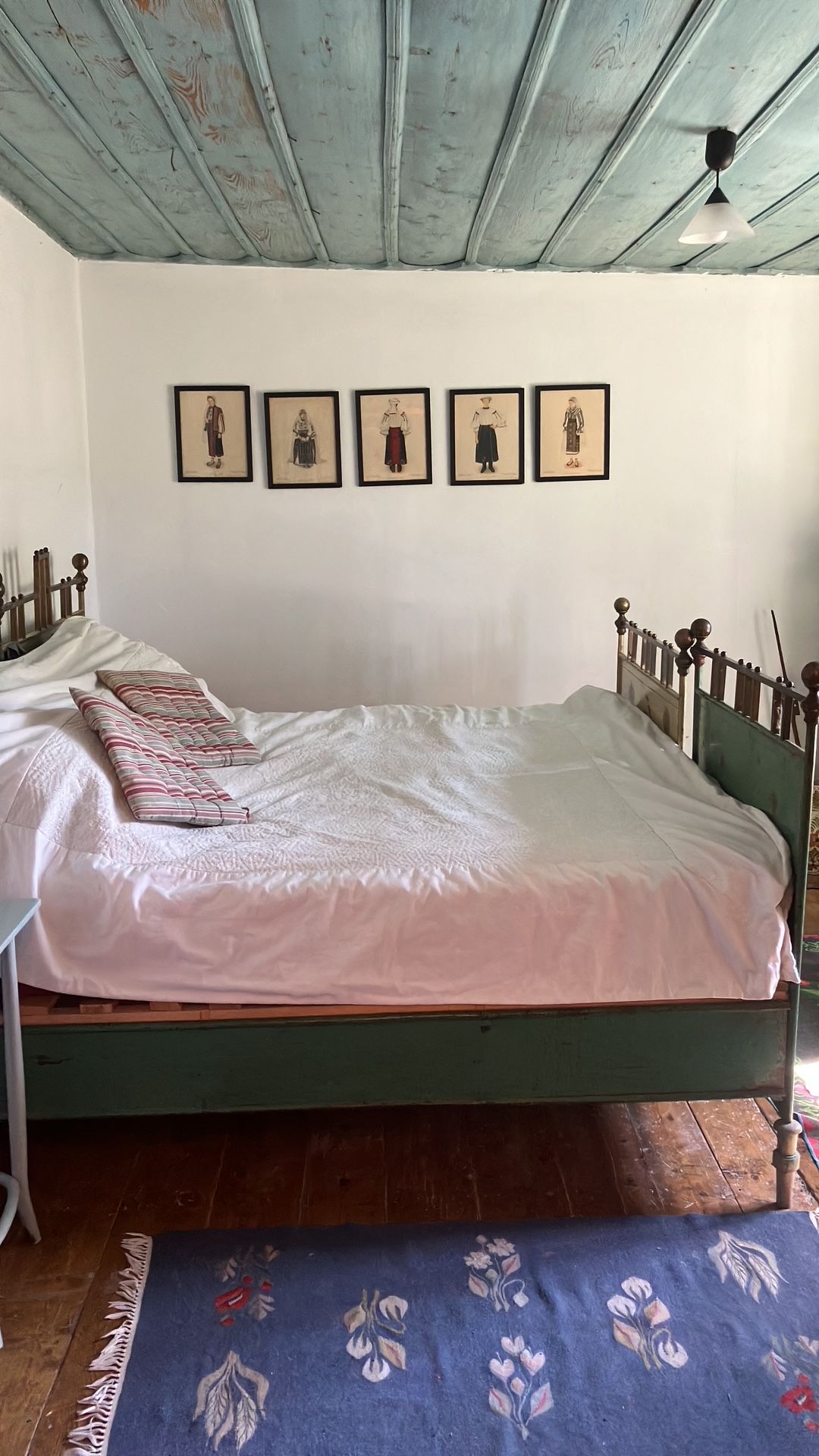 Une pièce comprenant un lit, une petite table et un mur orné de tableaux encadrés.