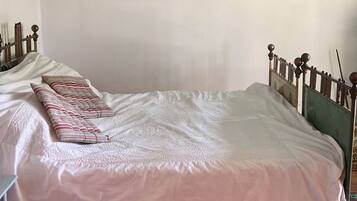 Une pièce comprenant un lit, une petite table et un mur orné de tableaux encadrés.