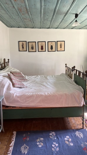 A room with a bed, a small table, and a wall with framed pictures.