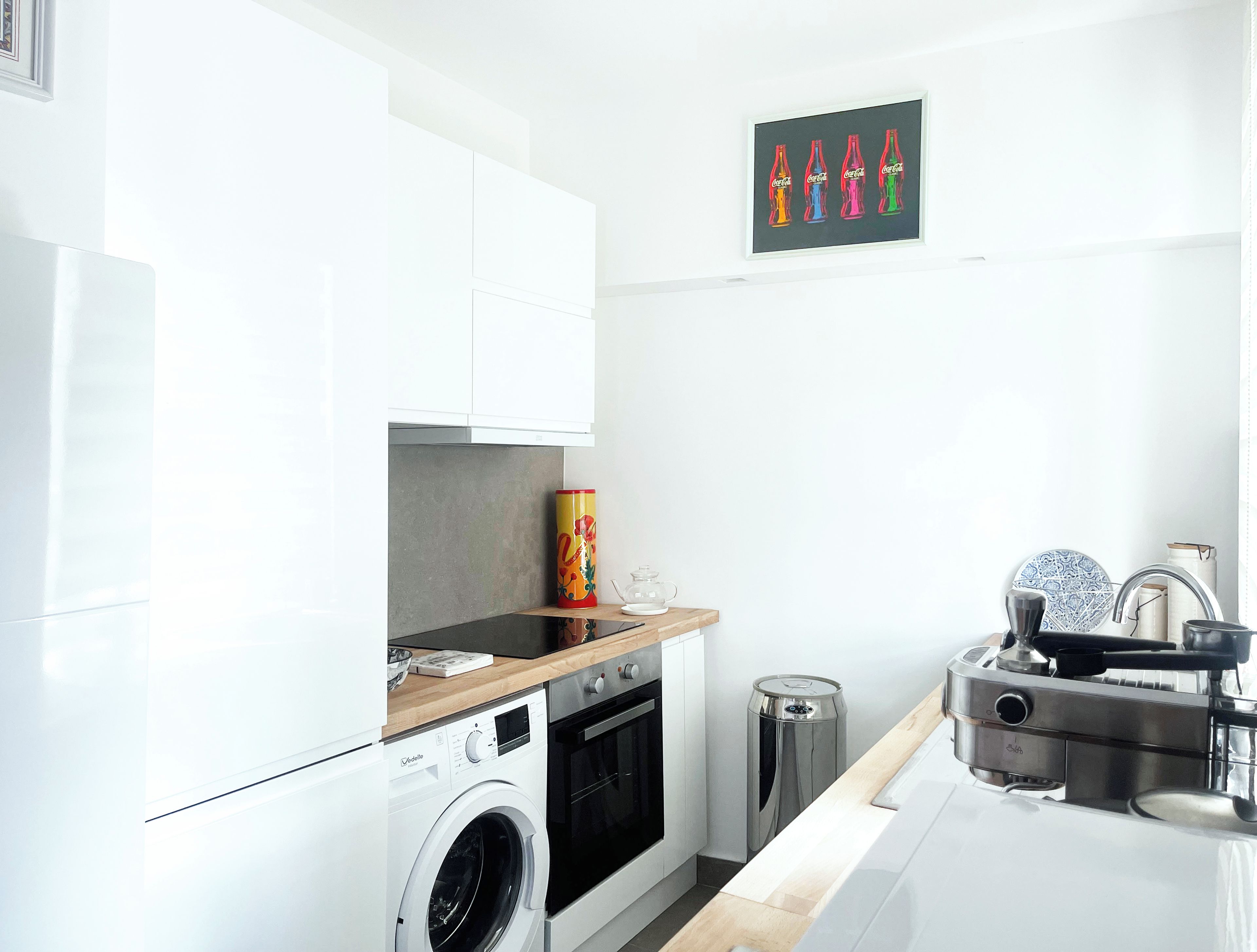 A modern kitchen with a washing machine, oven, and a coffee machine.
