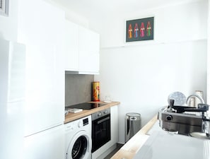 A modern kitchen with a washing machine, oven, and a coffee machine.
