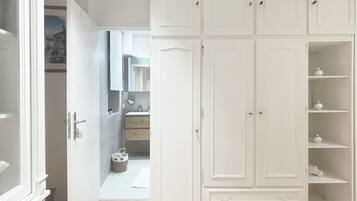 Una habitación con un armario grande de color blanco, piso de madera y una puerta que da a otra estancia.