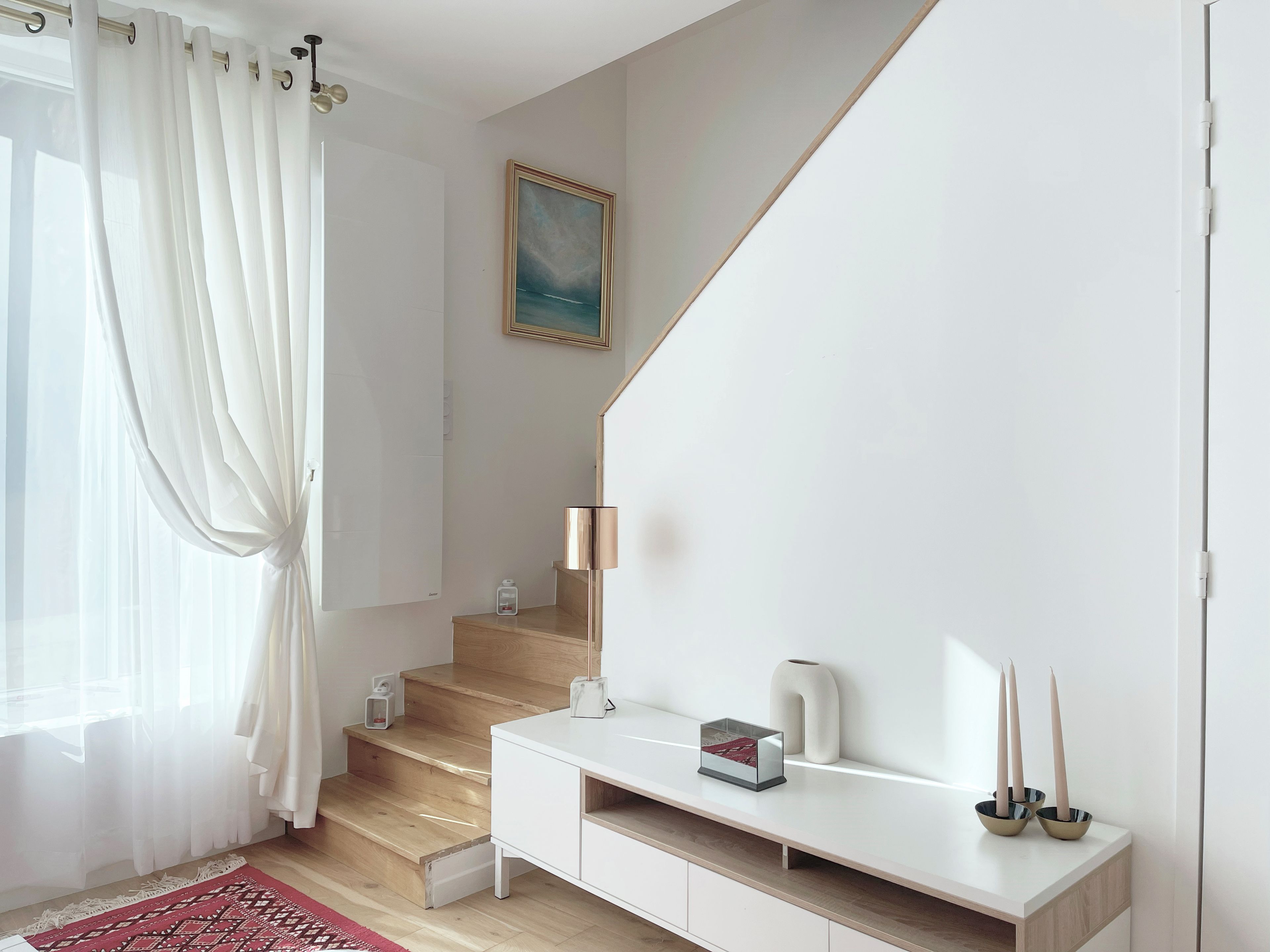 Een modern interieur met een trap, een witte console tafel en een schilderij aan de muur.