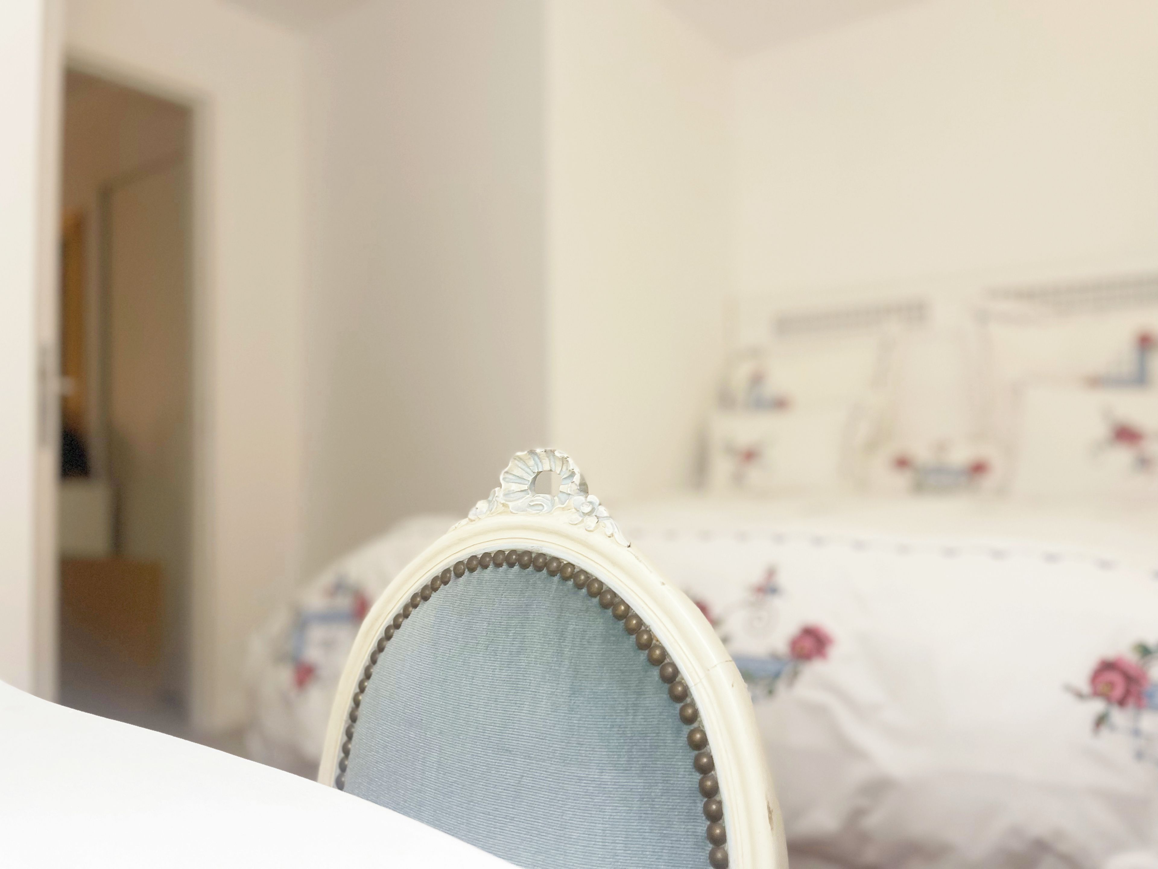 A bedroom with a bed featuring floral bedding and a headboard with decorative elements.