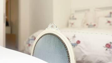 A bedroom with a bed featuring floral bedding and a headboard with decorative elements.