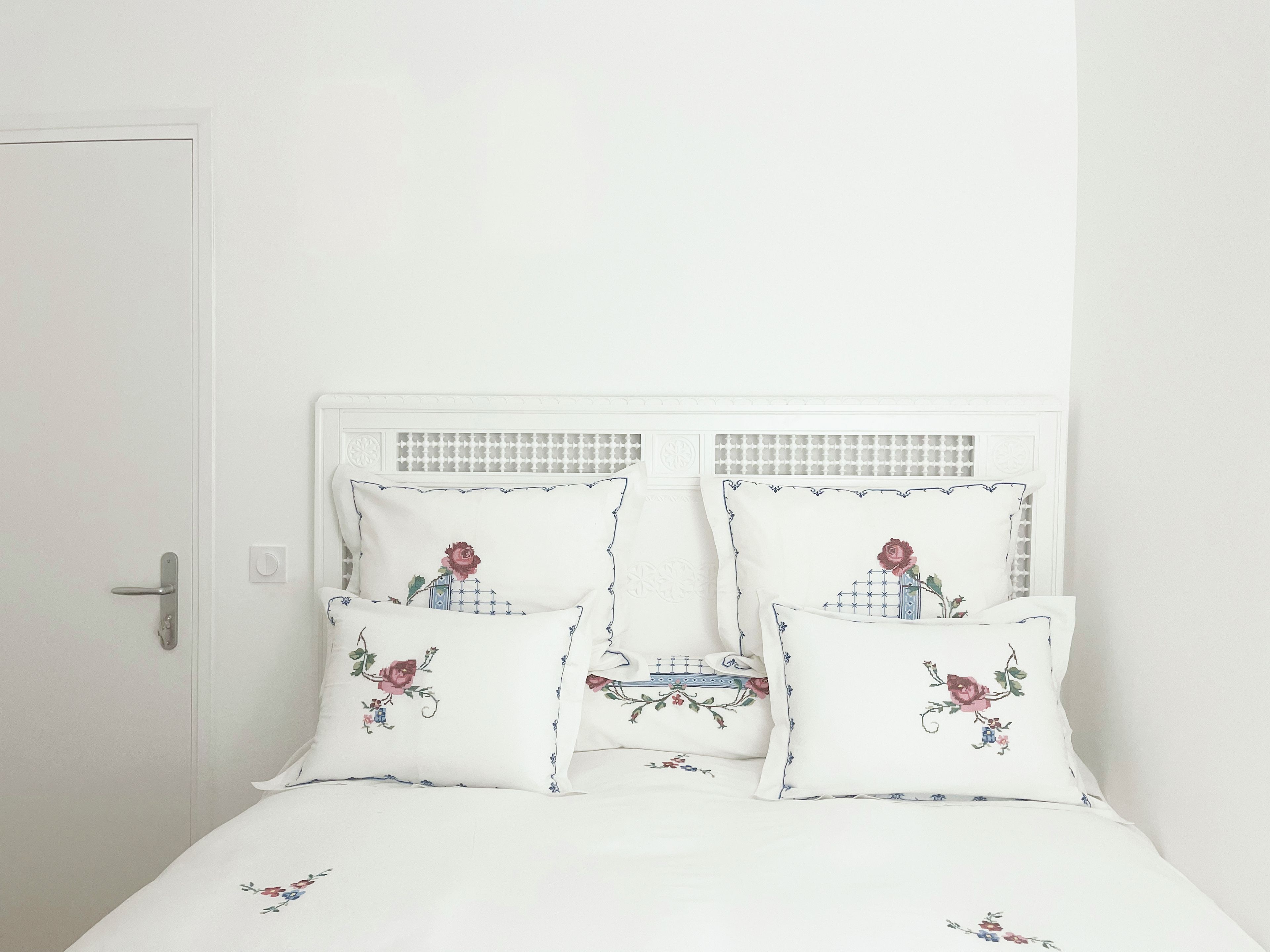 Ein Bett mit weißem Kopfteil und Kissen mit Blumenmuster.