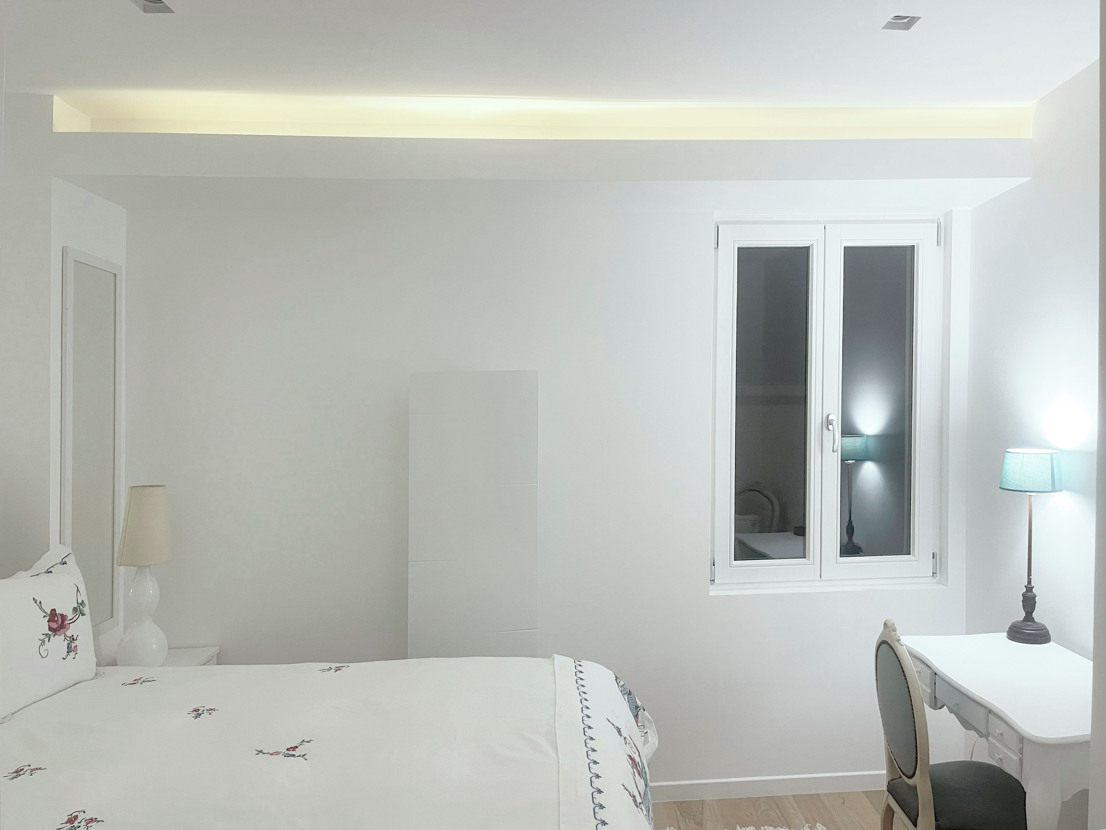 Un dormitorio con cama, escritorio, silla, ventana y armario.