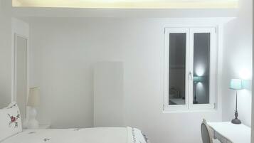 Un dormitorio con cama, escritorio, silla, ventana y armario.