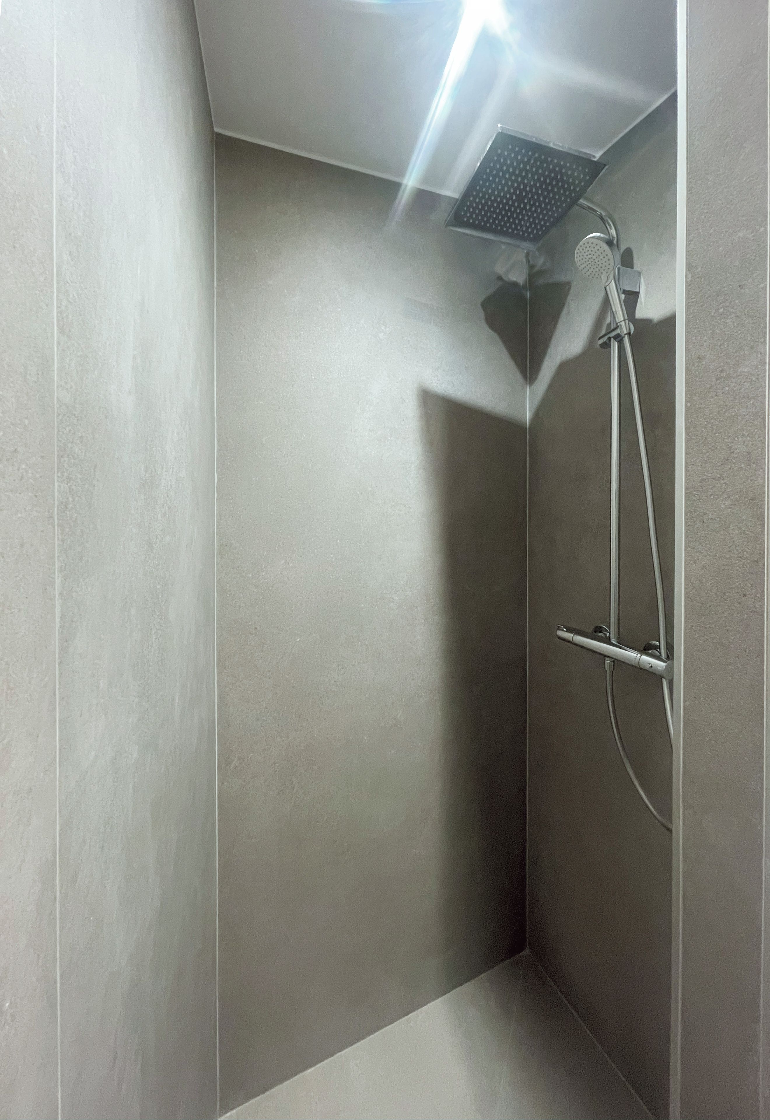 A modern shower with a handheld showerhead and a wall-mounted control panel.