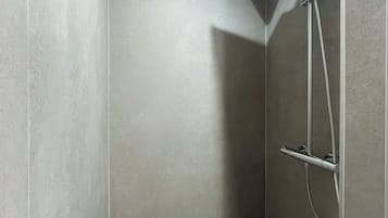 A modern shower with a handheld showerhead and a wall-mounted control panel.
