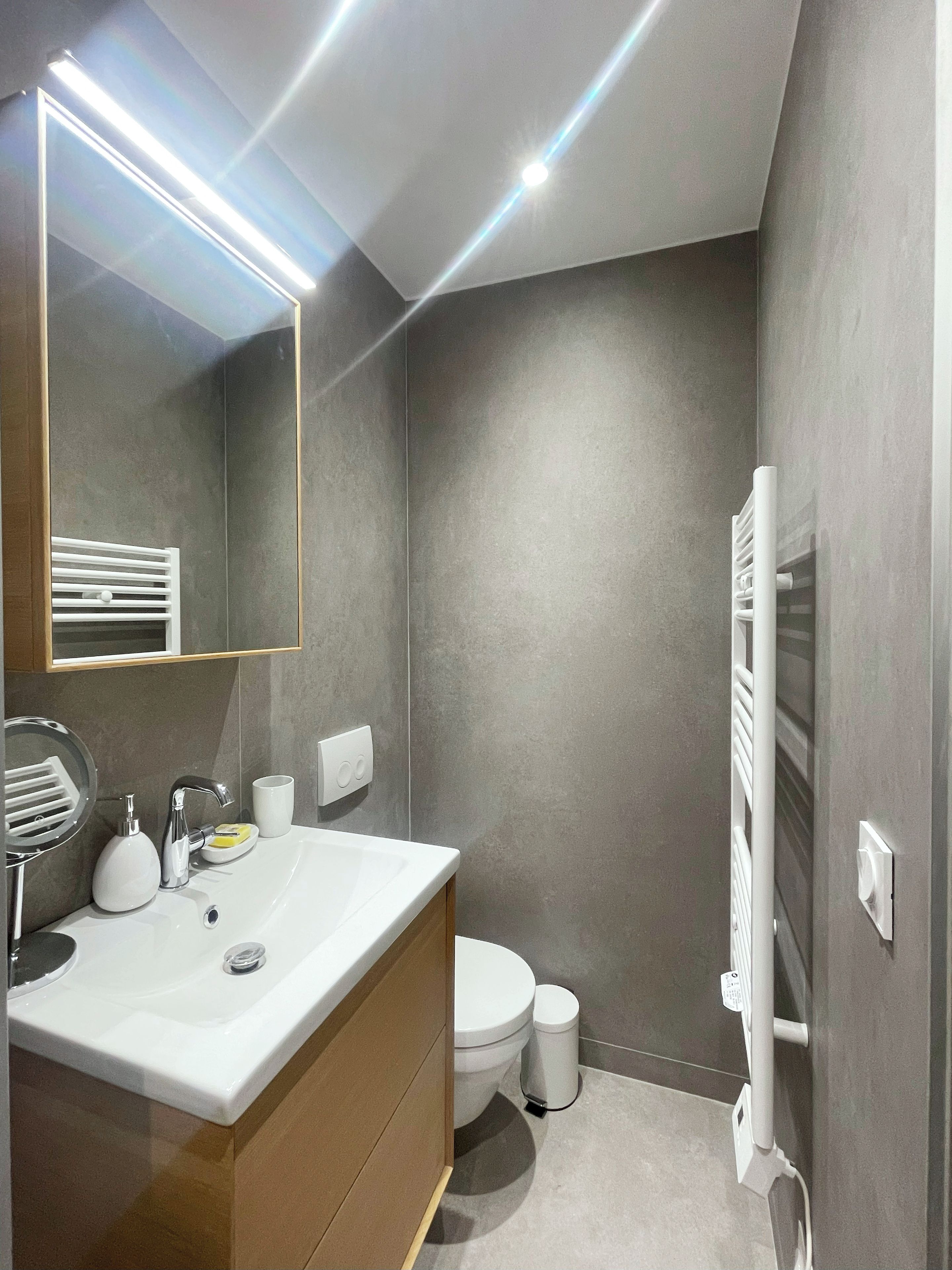 Ein modernes Badezimmer mit einem weißen Waschbecken, einem Spiegel und einem Handtuchhalter.
