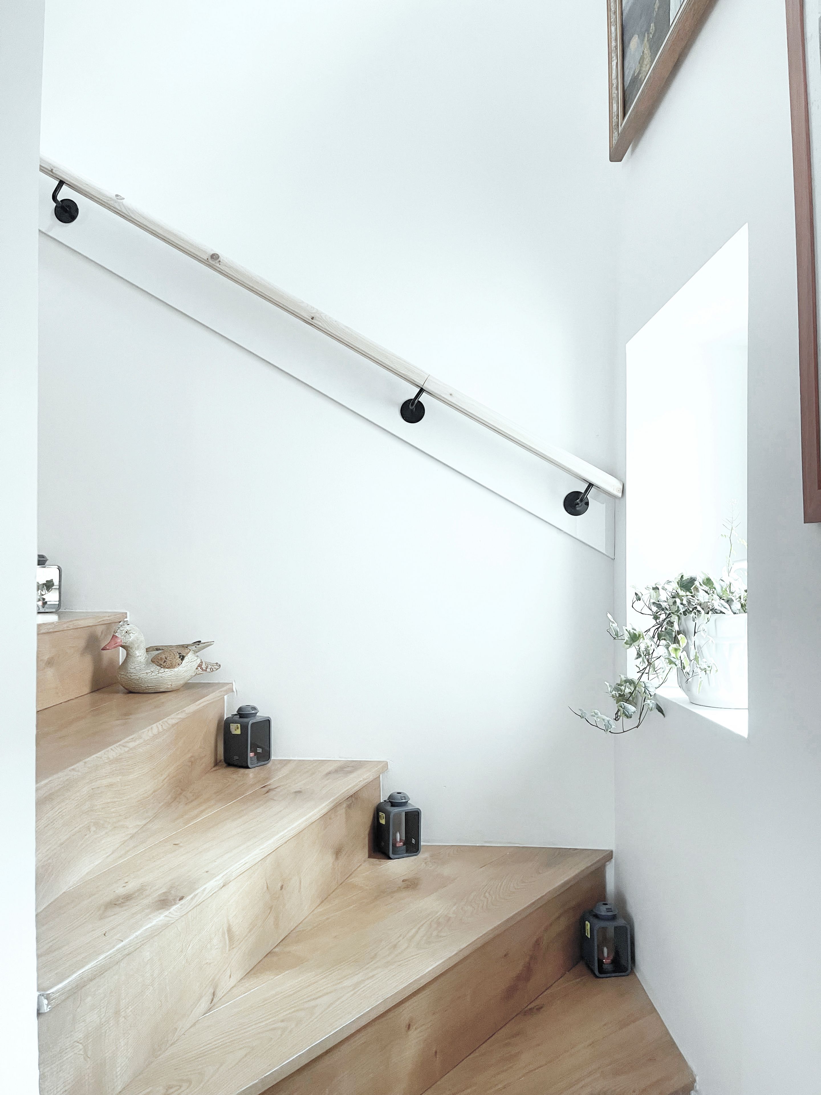 Un escalier avec des marches en bois, une rampe et un luminaire fixé au mur.