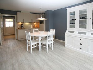 Una cocina moderna con armarios blancos, una mesa redonda y sillas.