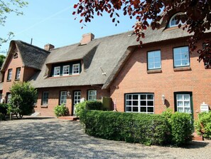 A traditional brick building with a thatched roof, multiple windows, and a gravel driveway. - Kiek Ut 9, Holiday Apartment 3 (Wyk auf Foehr)
