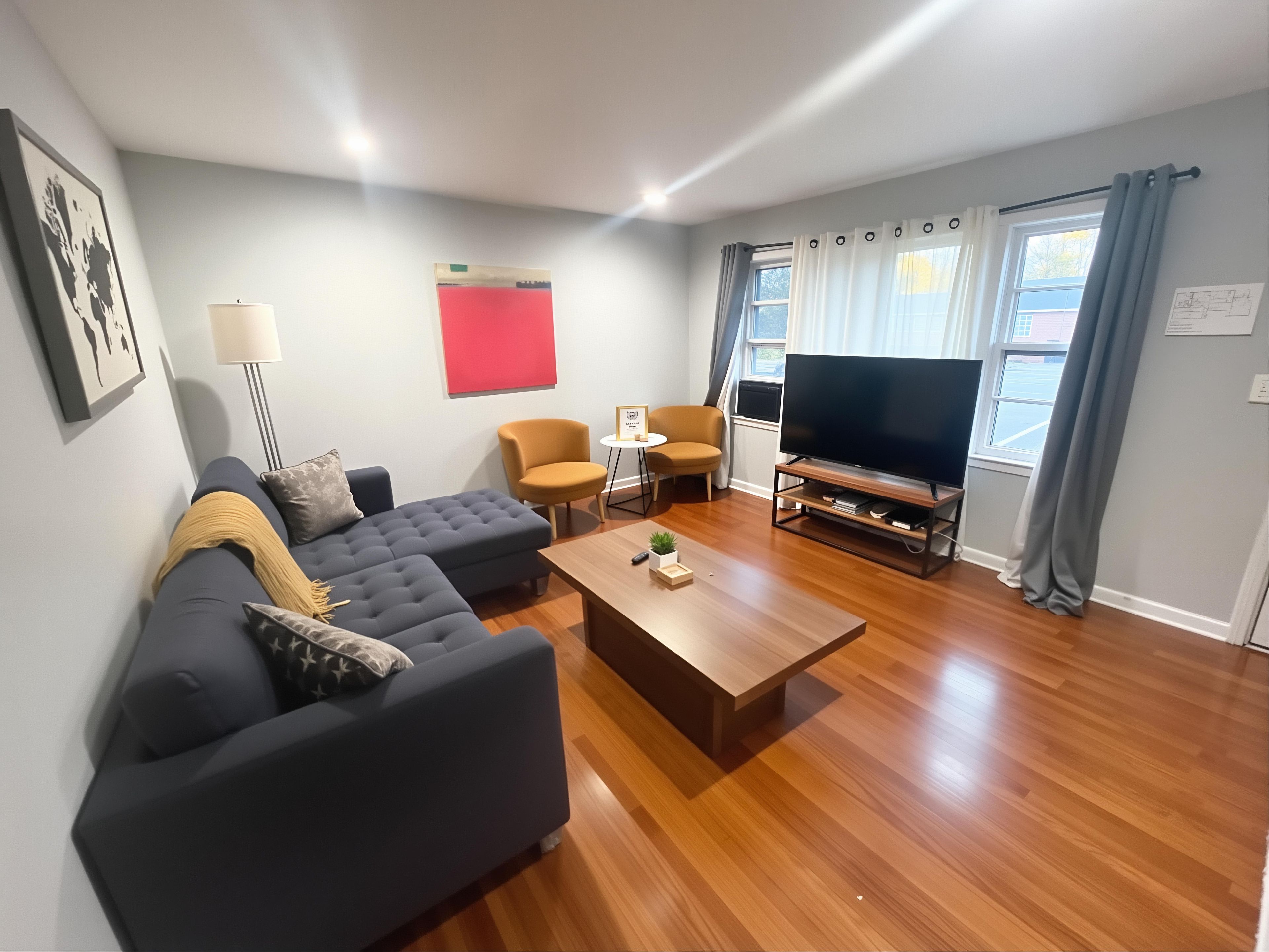 A modern living room with a sectional sofa, a coffee table, a TV, and a dining area with chairs.