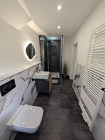 A modern bathroom with a white sink, a mirror, and a shower area.