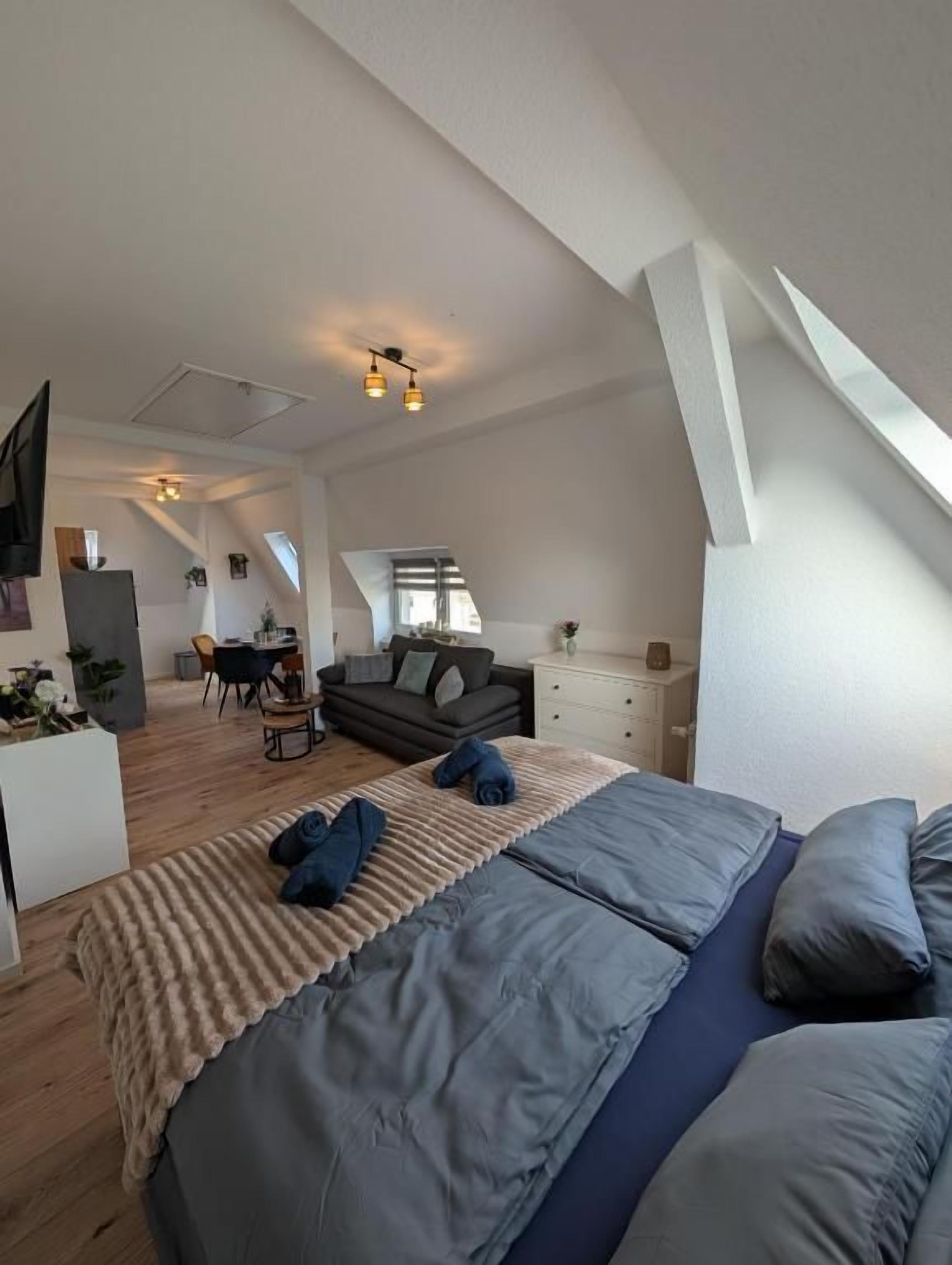 A bedroom with a large bed, a desk, and a sofa.