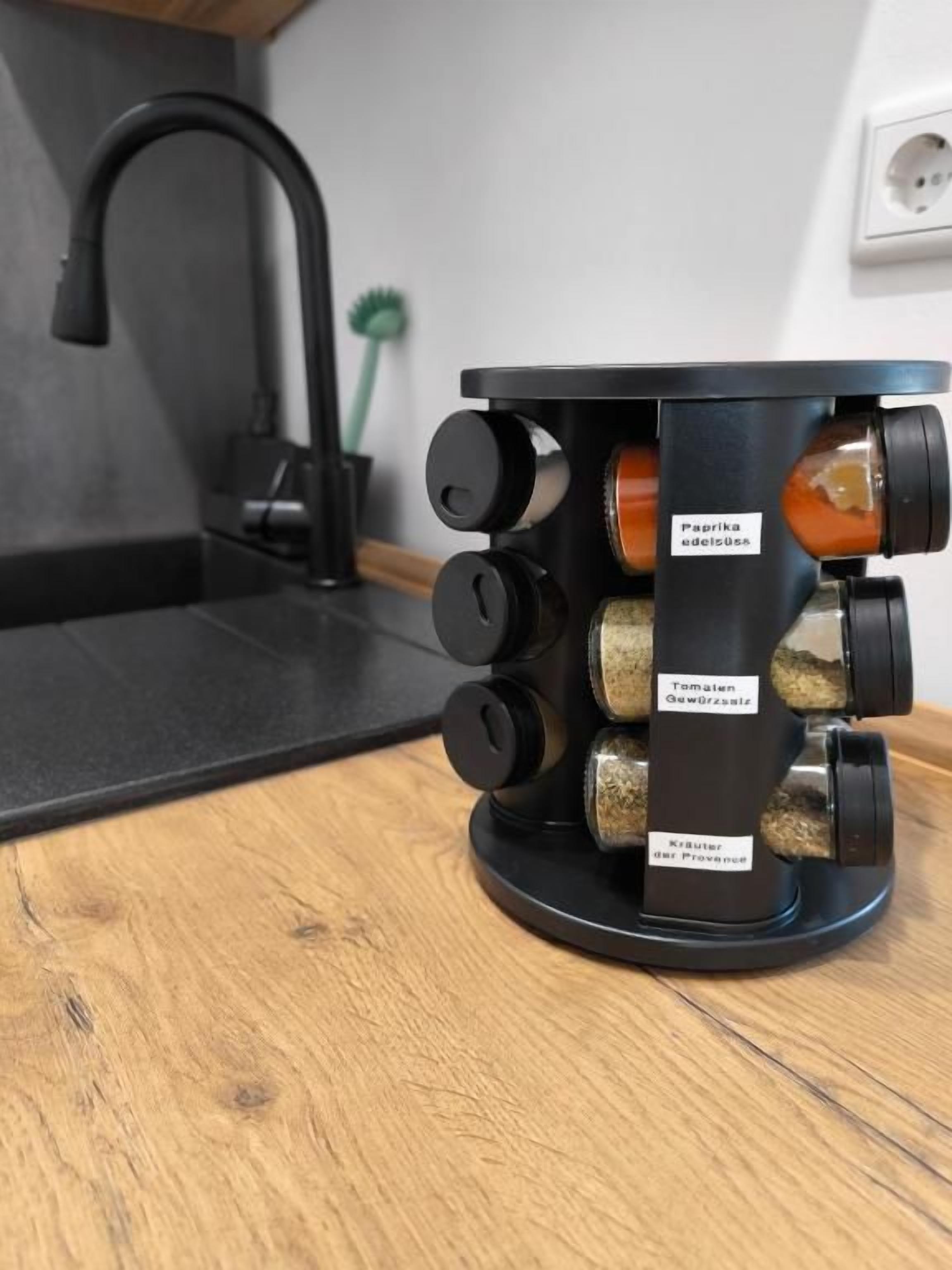 A kitchen with a black faucet, a wooden countertop, and a spice rack with labeled containers.