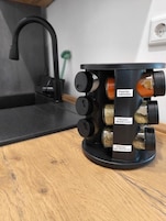 A kitchen with a black faucet, a wooden countertop, and a spice rack with labeled containers.