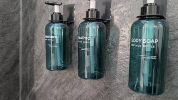 Three toiletry bottles on a textured wall.