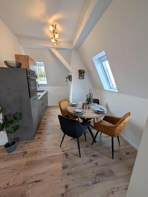 Cocina compacta con electrodomésticos modernos, comedor con mesa redonda y sillas, y tragaluz que proporciona luz natural.