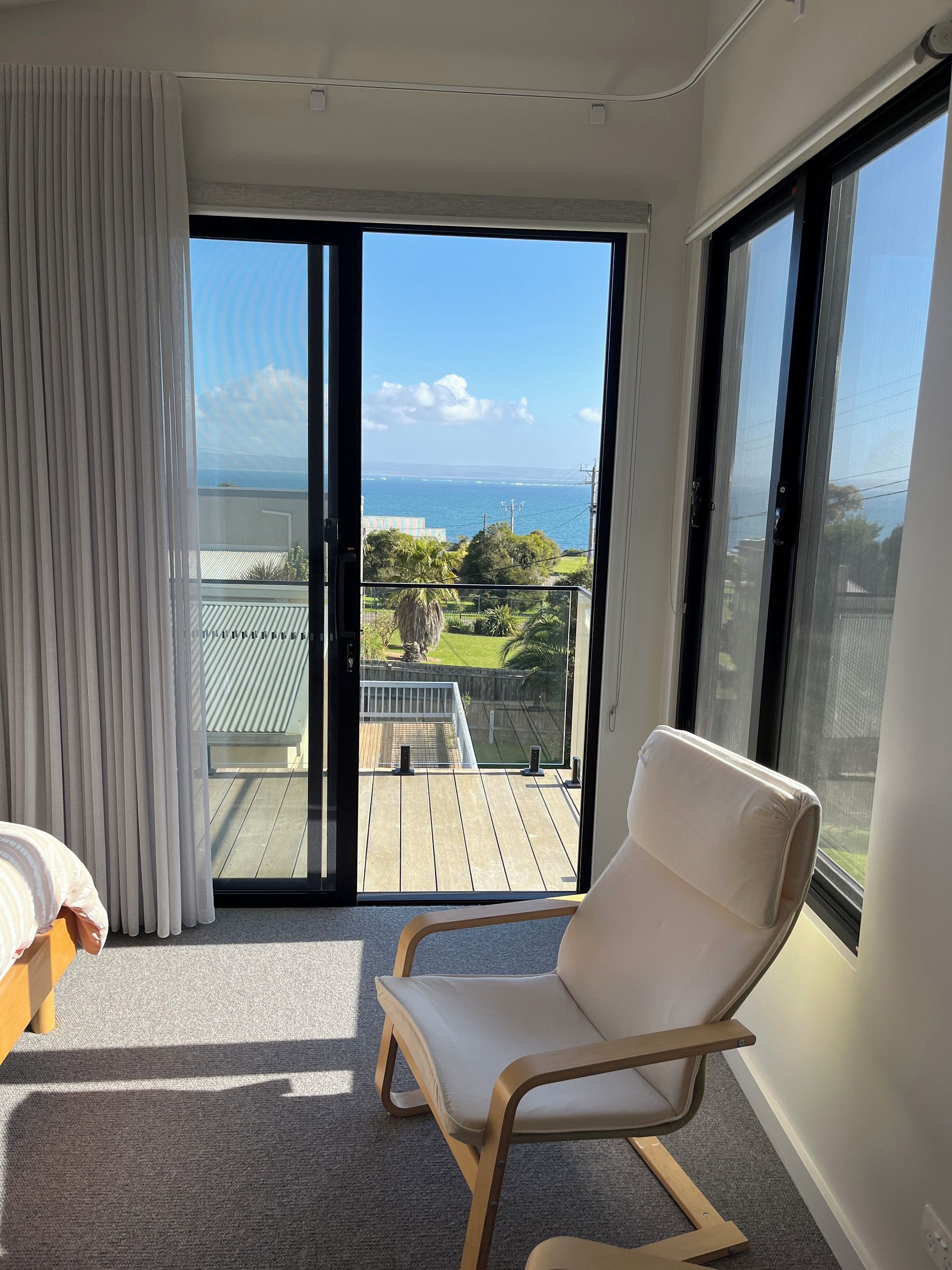 Een kamer met een grote schuifglazen deur die uitkomt op een balkon met uitzicht op de oceaan.