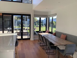 A modern interior with a dining area, a kitchen, and a large sliding glass door leading to an outdoor space. - Fisher St beach house Ventnor 150 metres to beach, veiws, spacious (Ventnor)