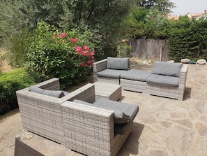 Un patio con mobiliario de mimbre y una pequeña fuente de agua.