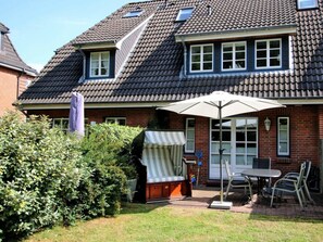A residential house with a tiled roof, a covered outdoor seating area, and a brick exterior. - Holiday Apartment in Fohr With 2 Bedrooms (Wyk auf Foehr)