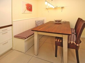 A dining area with a wooden table, bench seating, and a wall-mounted shelf with lights. - Holiday Apartment in Fohr With 2 Bedrooms (Wyk auf Foehr)