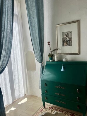 Ein Zimmer mit einem grünen Schrank, einem gerahmten Bild und einer Topfpflanze.