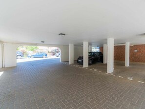 Un espace de stationnement intérieur doté d’un sol en briques et de piliers blancs.