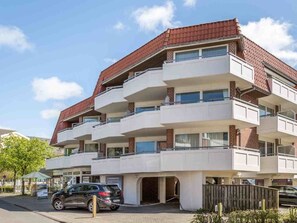 A multi-story residential building with balconies, a parking area, and a visible entrance. - Holiday Apartment With 2 Bedrooms (St. Peter-Ording)