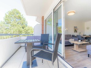 A balcony with a table and chairs, a sofa, and a dining area with chairs and a table. - Holiday Apartment With 2 Bedrooms (St. Peter-Ording)