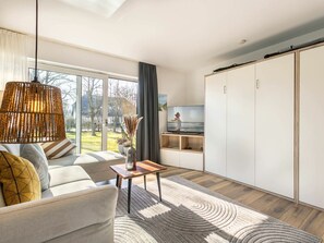 A modern living room with a sofa, a coffee table, a TV, and a sliding wardrobe. - 1 in the Westmarken Building (St. Peter-Ording)