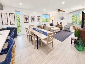 A spacious living area with a dining table, sofas, and a television. - Ocean Grand Retreat is a premiere luxury condo next to Smathers Beach (Key West)