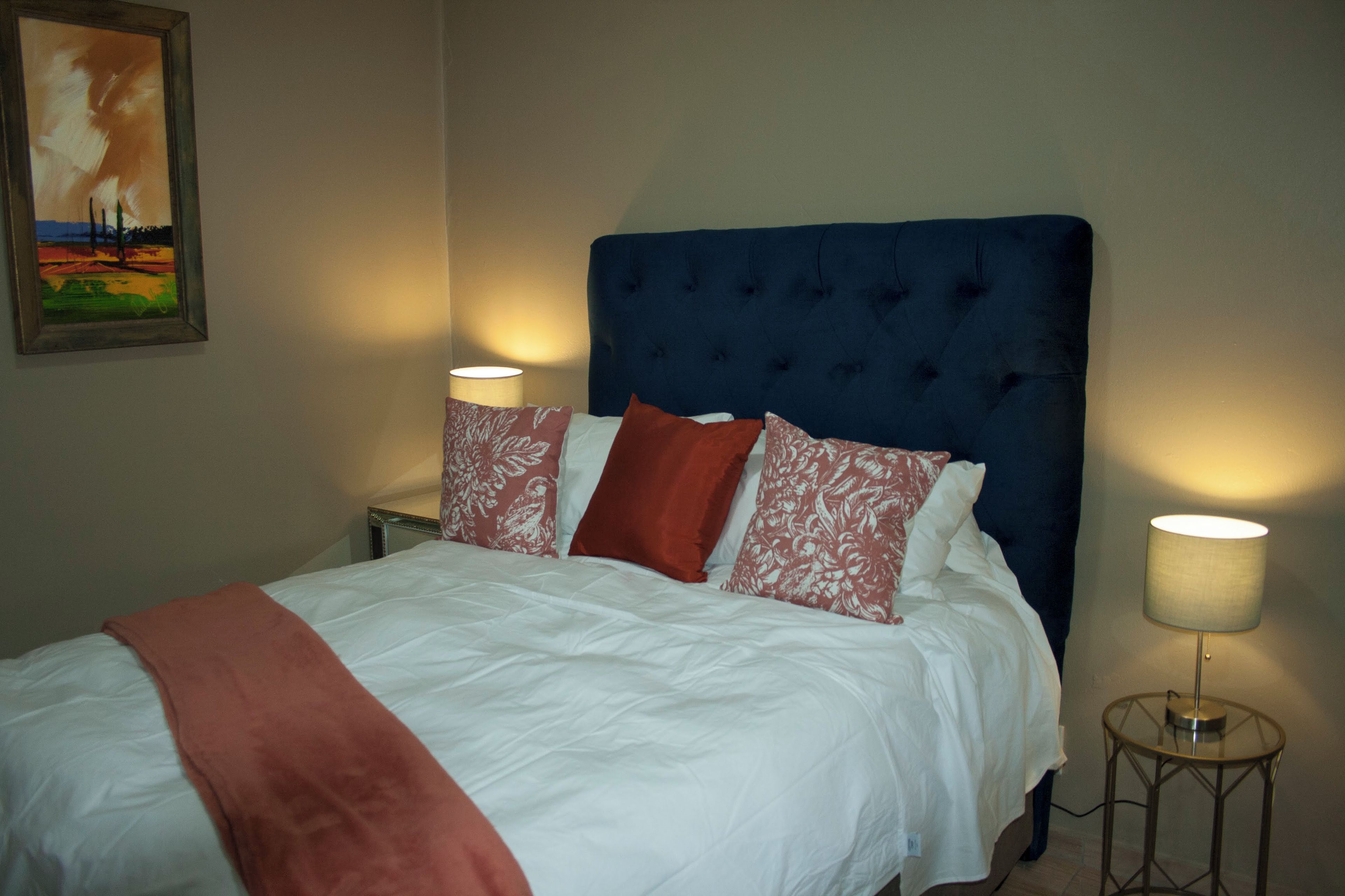 A bed with white bedding, a blue upholstered headboard, and two bedside lamps.