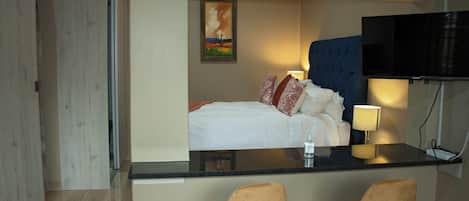 Una habitación de hotel con cama, televisión, escritorio y dos sillas.