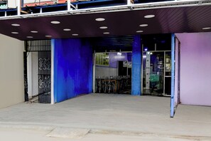 Entrada de un edificio con toldo azul, reja metálica y un letrero que dice 'Welcome'.