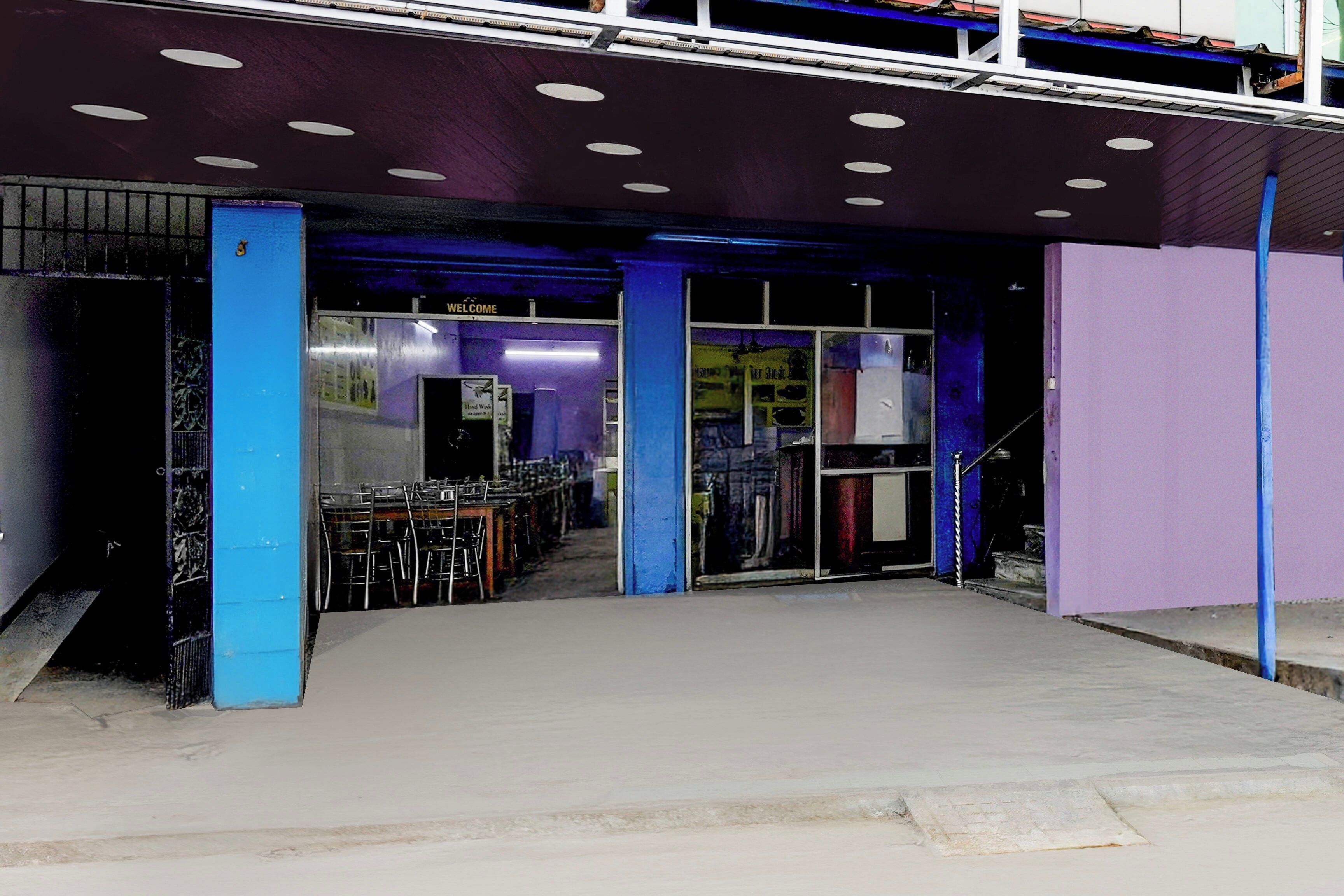 A building entrance with a ramp leading up to a door, a sign above the door, and a staircase to the right.