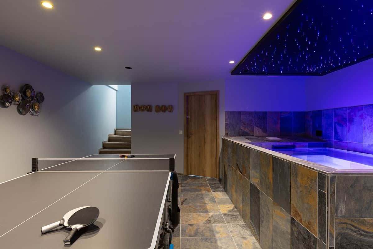 Une pièce avec une table de ping-pong, une porte en bois et un mur décoré de motifs étoilés.