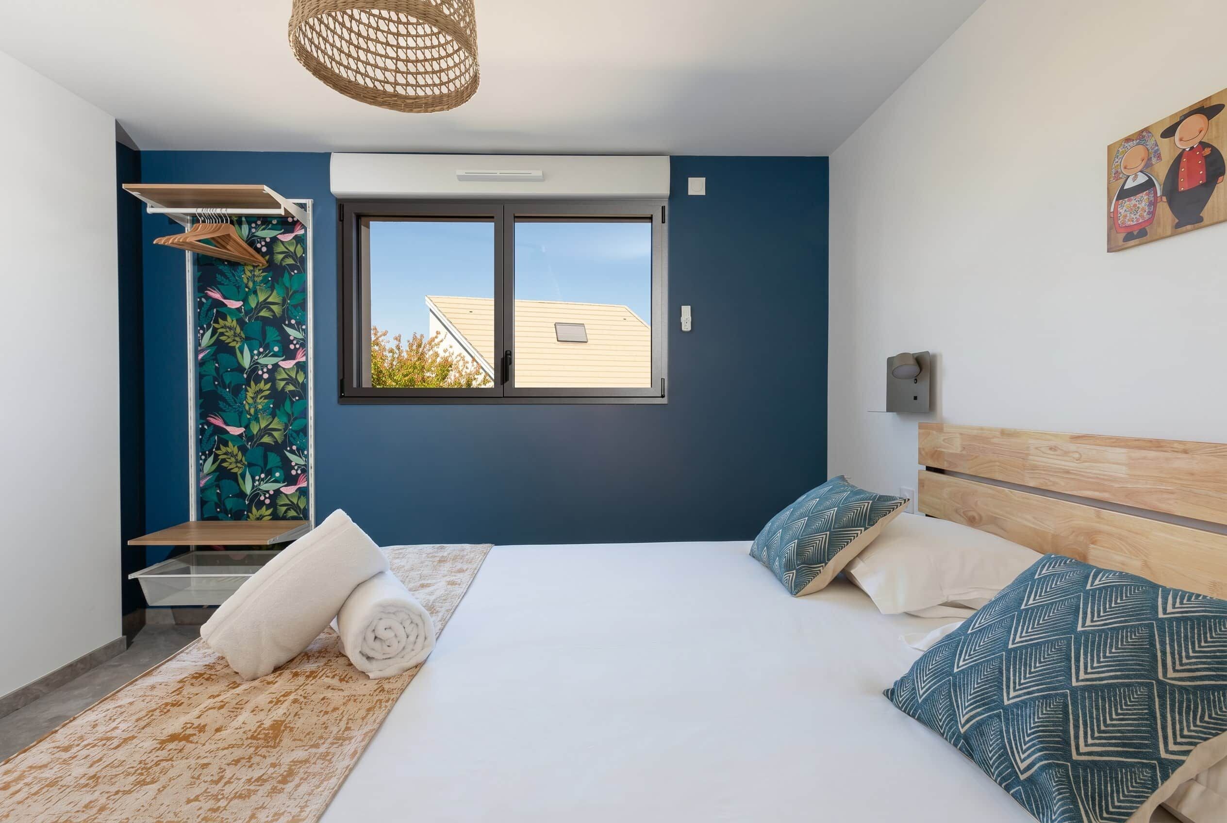 Een slaapkamer met een bed, een raam, een douche en een muur met een schilderij.