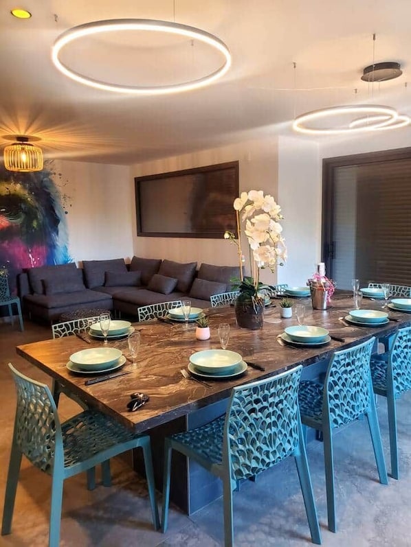 Een eetgedeelte met een houten tafel voor zes personen, omringd door blauwe stoelen met een geometrisch patroon.