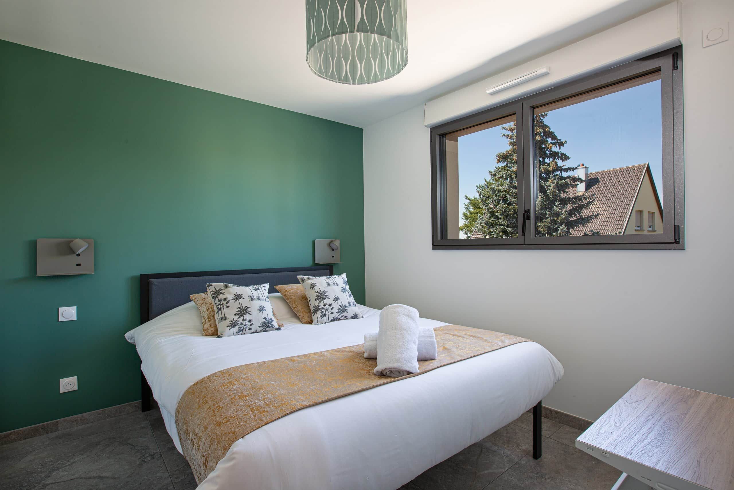 Une chambre à coucher avec un lit, une fenêtre et une vue sur un bâtiment à l’extérieur.