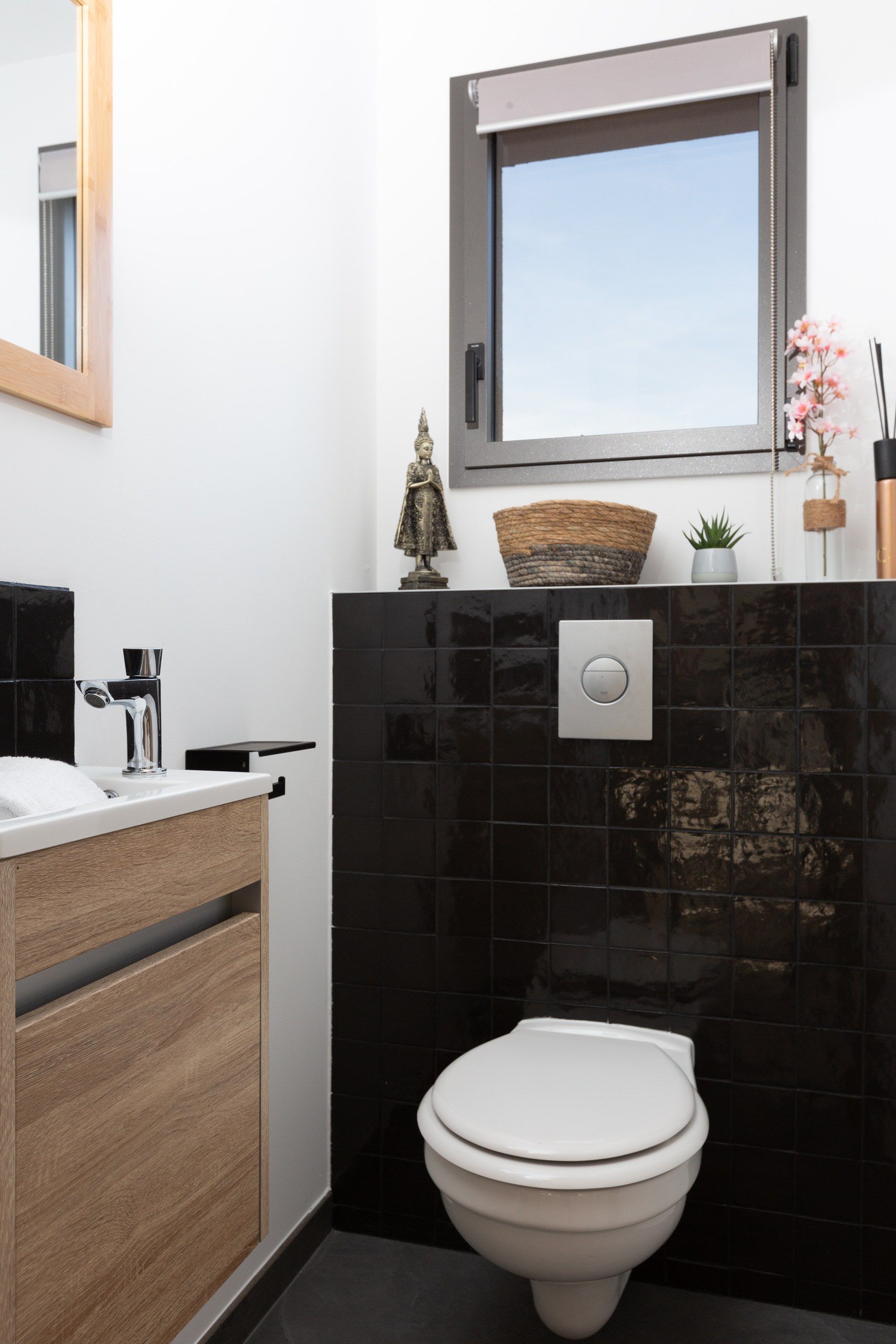 Une salle de bain moderne comprenant des toilettes, un lavabo avec un meuble en bois, un miroir et une fenêtre située au-dessus du lavabo.