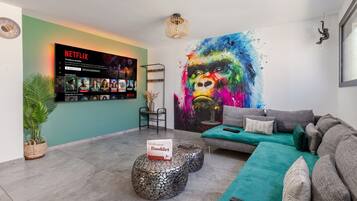 Een moderne woonkamer met een Netflix-scherm, een kleurrijk abstract schilderij en een gezellige zithoek.