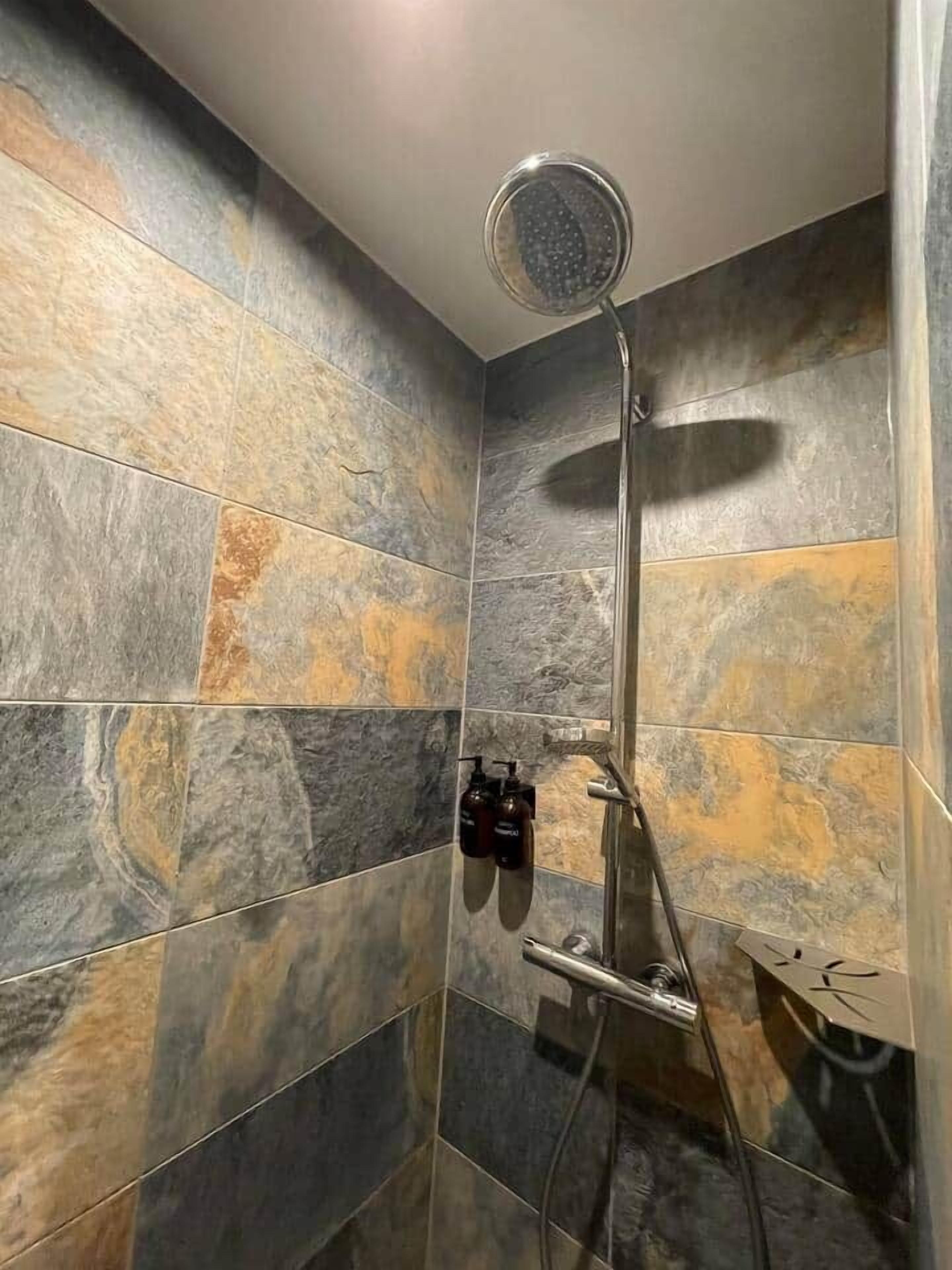Une douche équipée d’un pommeau de douche à main, d’un autre pommeau de douche à main et d’un troisième pommeau de douche à main.