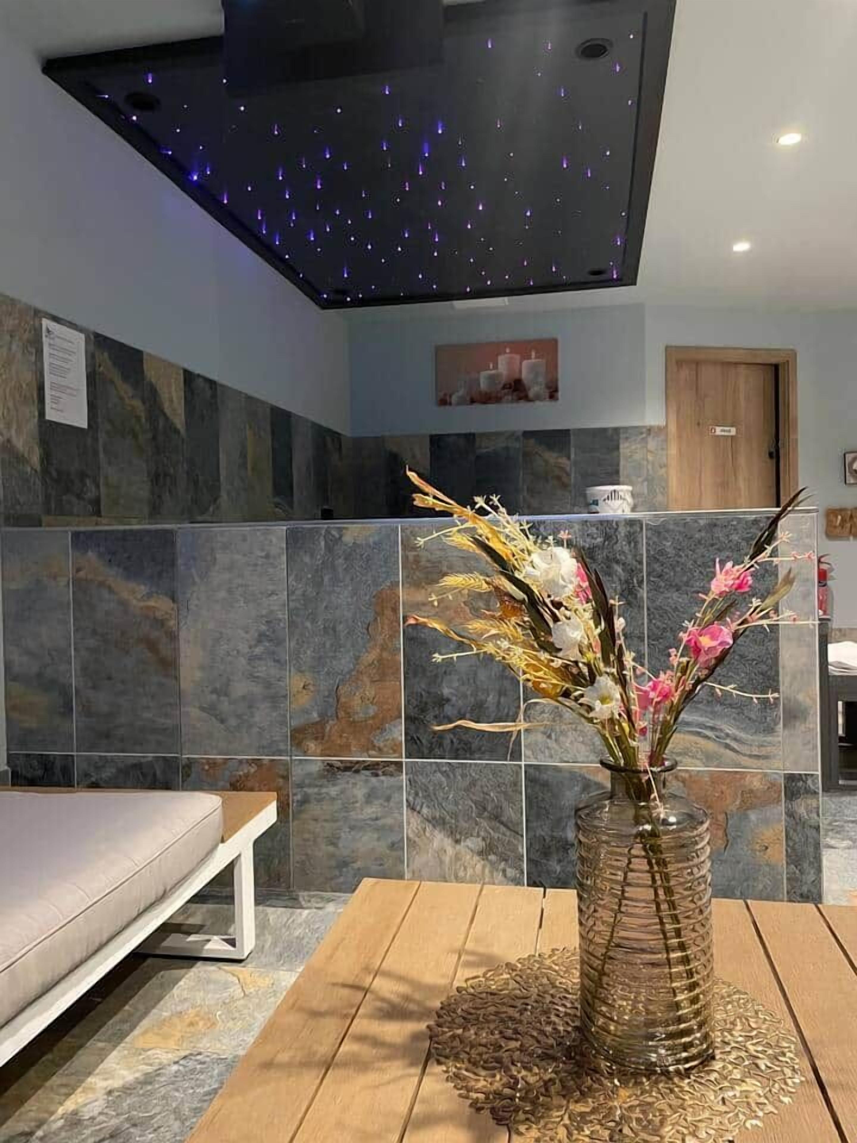 Un interno moderno con un lampadario, un vaso con fiori e una panca.